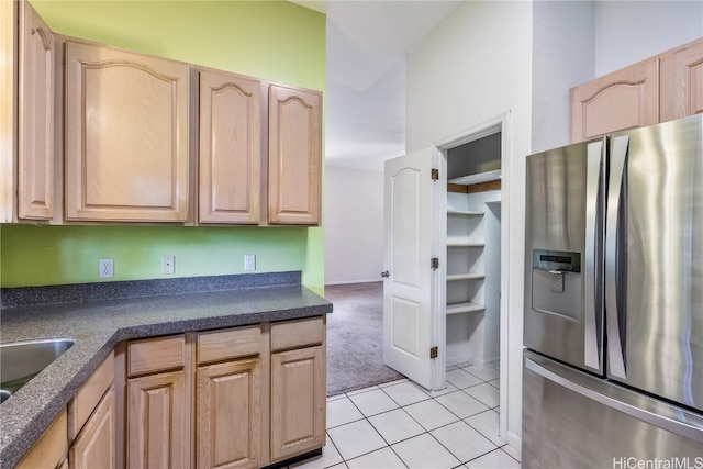 kitchen with stainless steel fridge, sink, light carpet, and light brown cabinetry