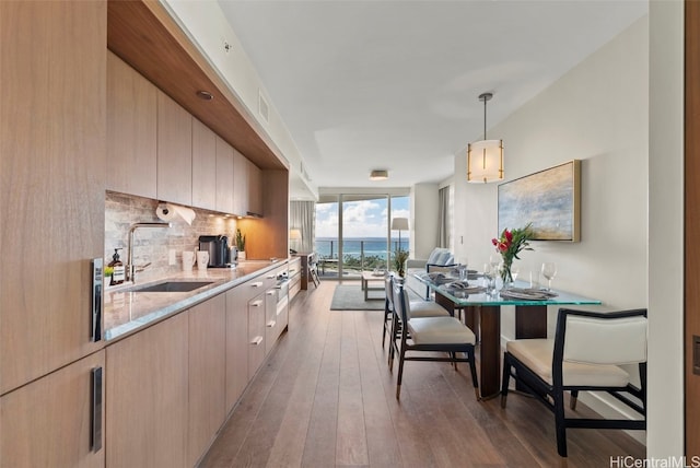 kitchen with dark hardwood / wood-style floors, sink, light brown cabinetry, and pendant lighting