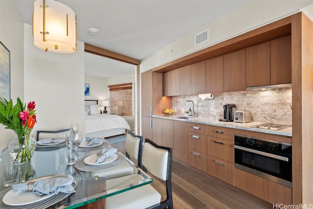 kitchen featuring oven, sink, gas cooktop, decorative backsplash, and dark hardwood / wood-style floors