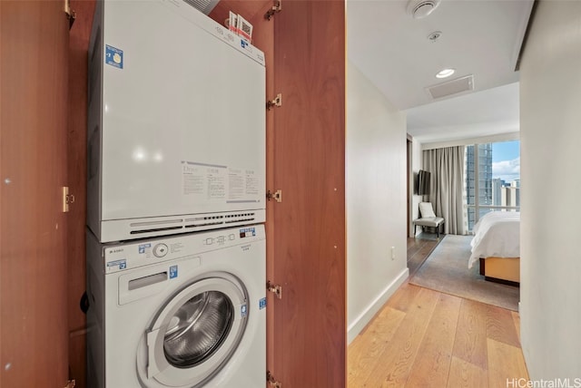 washroom featuring stacked washer / dryer and light hardwood / wood-style floors