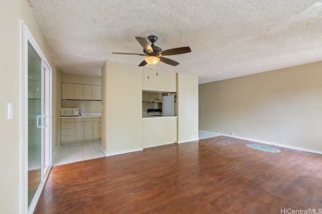 unfurnished living room with light hardwood / wood-style flooring, a textured ceiling, and ceiling fan