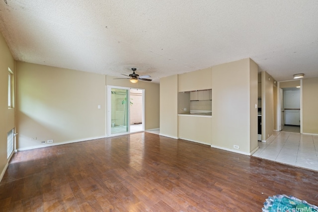 unfurnished living room with ceiling fan, hardwood / wood-style flooring, a textured ceiling, and built in features