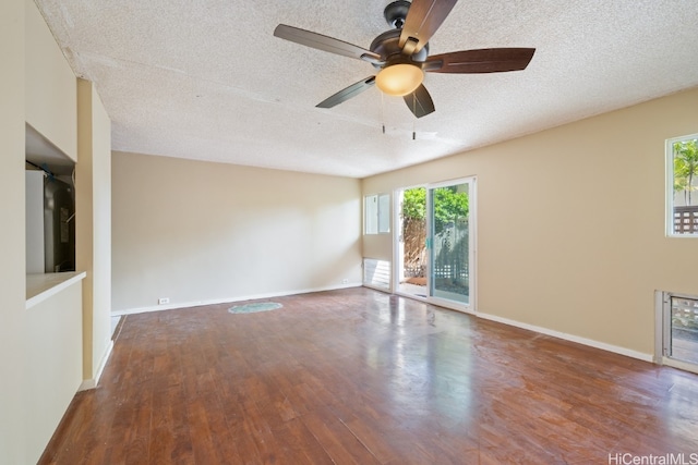 empty room with a textured ceiling, hardwood / wood-style flooring, and a healthy amount of sunlight