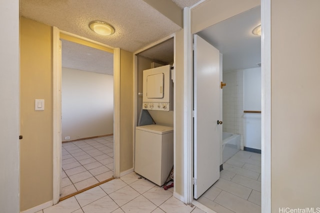 laundry area featuring light tile patterned flooring, a textured ceiling, and stacked washer / dryer