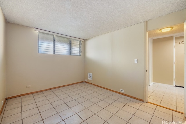 spare room with a textured ceiling and light tile patterned flooring