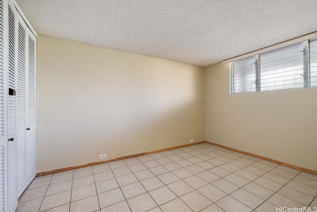 tiled spare room featuring a textured ceiling