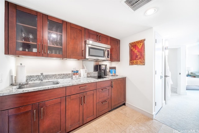 kitchen featuring black electric cooktop, sink, and light stone counters