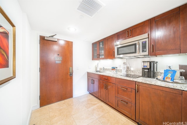 kitchen with light tile patterned flooring, black electric stovetop, and light stone counters