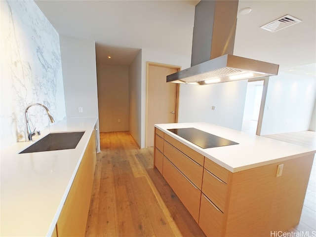 kitchen featuring sink, a kitchen island, island range hood, black electric cooktop, and light hardwood / wood-style floors