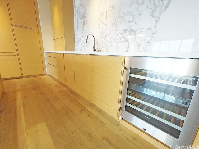 interior space featuring light hardwood / wood-style floors, wine cooler, sink, and light brown cabinetry