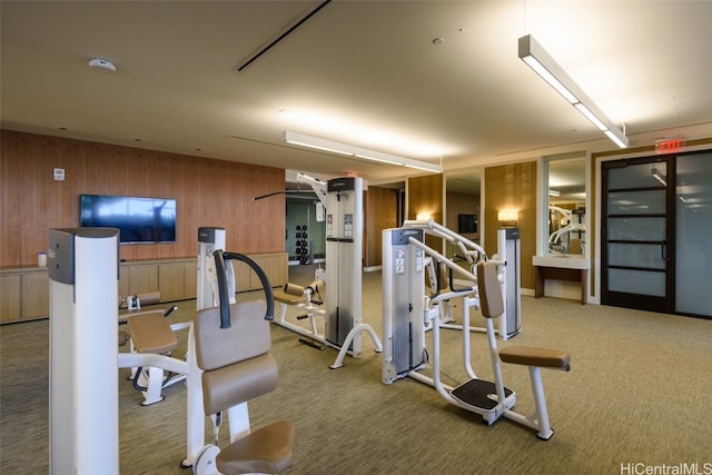 exercise room with carpet and wood walls