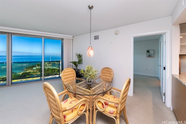 dining area with light colored carpet and a water view