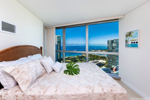 carpeted bedroom featuring a water view, expansive windows, and multiple windows