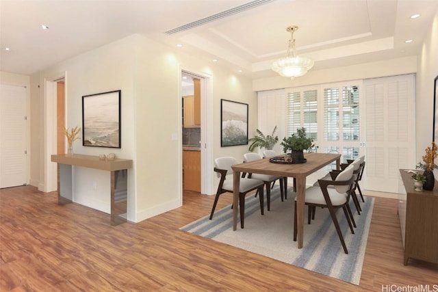 dining room featuring hardwood / wood-style floors and a tray ceiling