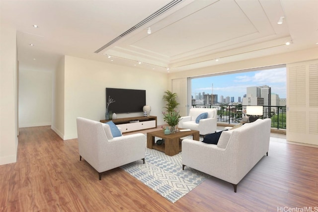 living room with light hardwood / wood-style flooring and a tray ceiling