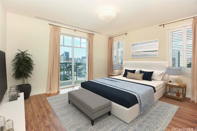 bedroom featuring access to outside, wood-type flooring, and multiple windows