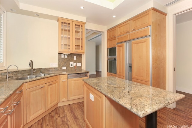 kitchen featuring oven, backsplash, sink, light wood-type flooring, and light stone counters