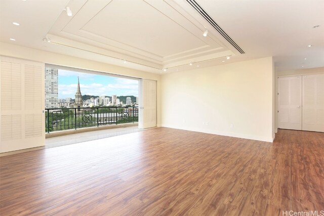 empty room featuring wood-type flooring and a raised ceiling