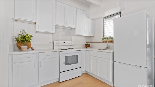 kitchen with white appliances, white cabinetry, and sink