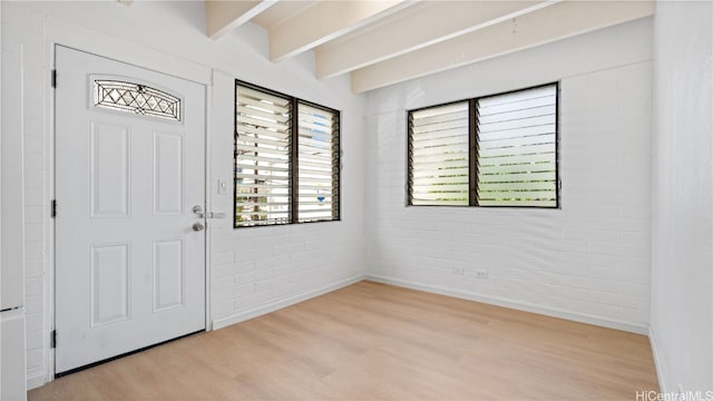 entryway featuring beam ceiling, brick wall, and light hardwood / wood-style flooring