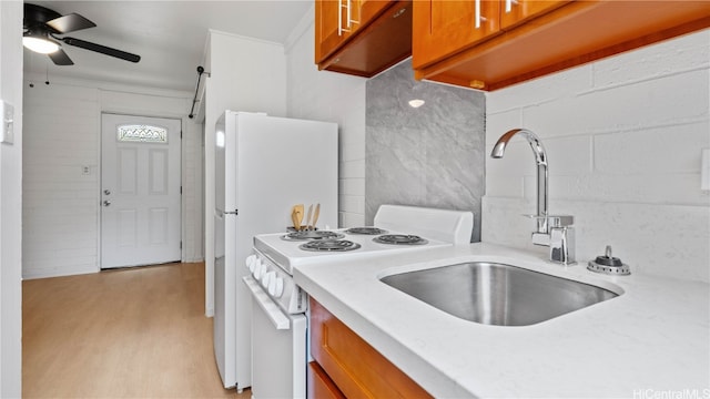 kitchen with white appliances, sink, light wood-type flooring, ceiling fan, and ornamental molding