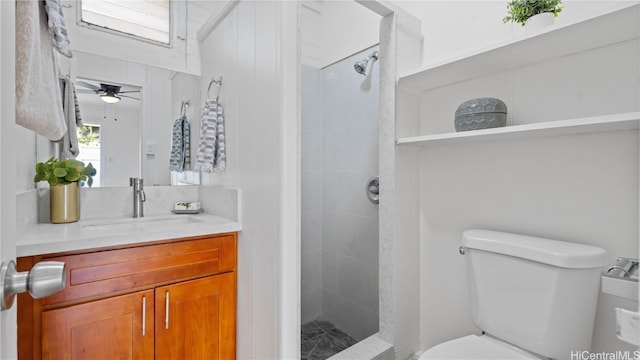 bathroom with vanity, toilet, tiled shower, and ceiling fan