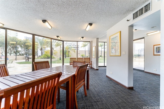 dining space featuring a wall of windows, a textured ceiling, and dark colored carpet