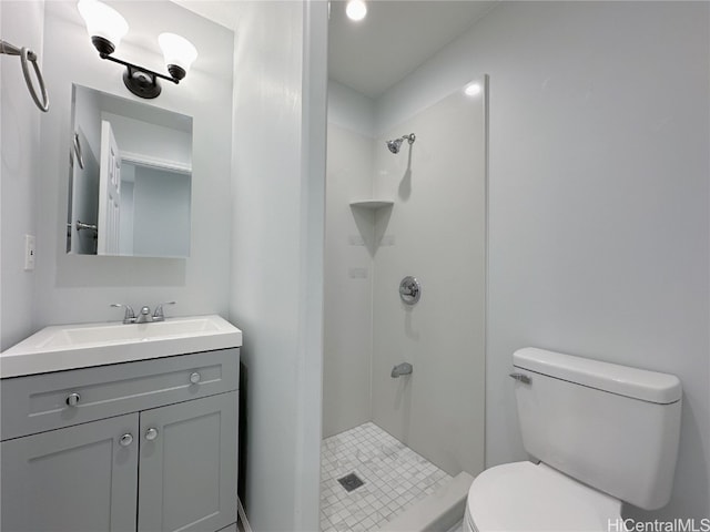 bathroom featuring vanity, a tile shower, and toilet