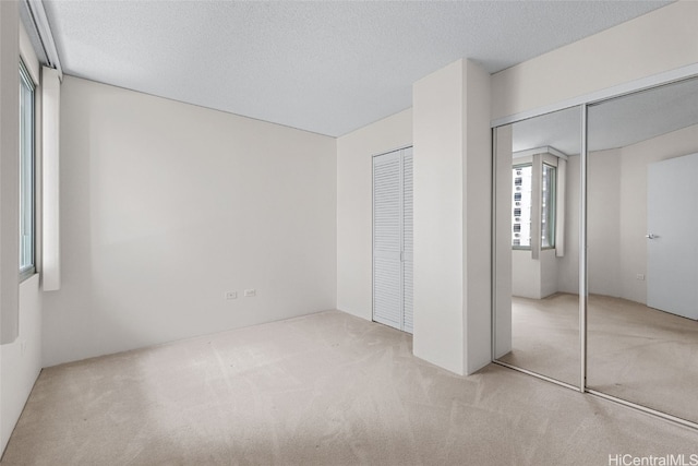 unfurnished bedroom featuring light carpet and a textured ceiling