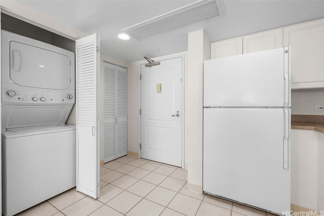 laundry area featuring light tile patterned floors and stacked washer and clothes dryer