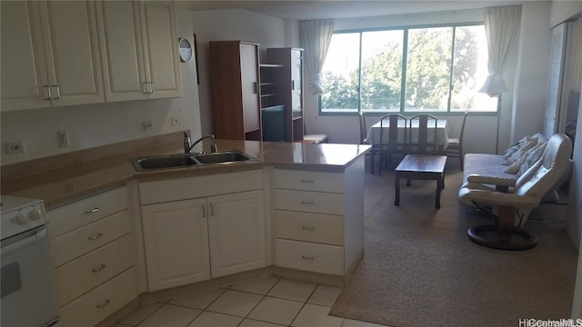 kitchen with light tile patterned flooring, sink, kitchen peninsula, white cabinetry, and white range oven