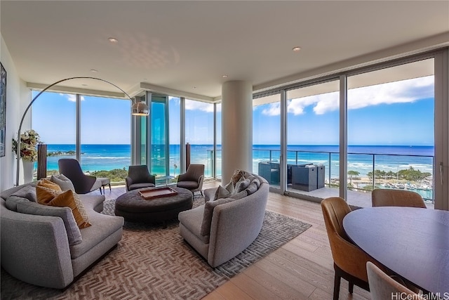 living room with a water view, plenty of natural light, light wood-type flooring, and a wall of windows