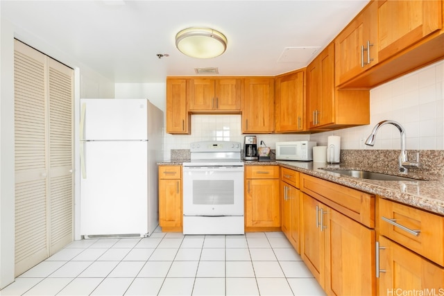 kitchen with tasteful backsplash, light tile patterned flooring, sink, light stone counters, and white appliances