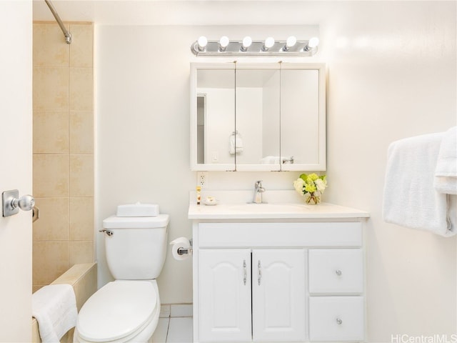 bathroom with vanity, a tile shower, toilet, and tile patterned flooring