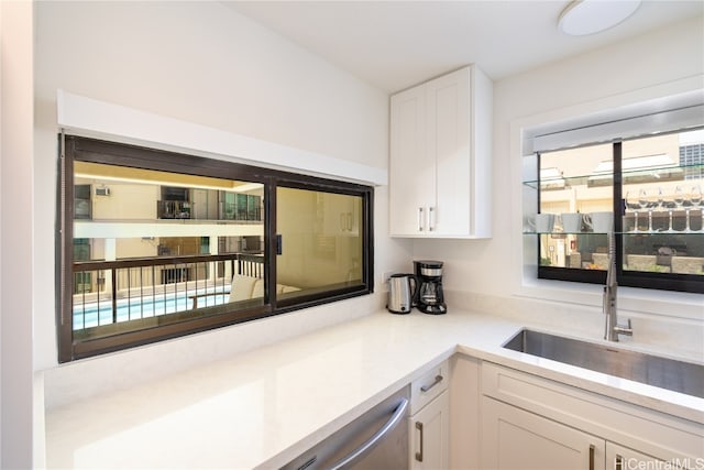 kitchen with stainless steel dishwasher, white cabinets, and sink