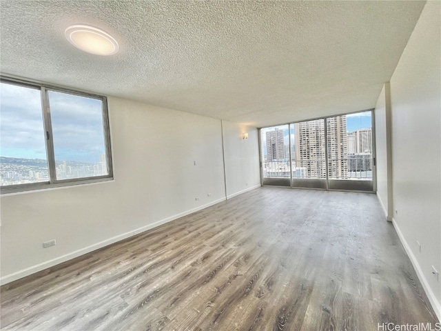 spare room with hardwood / wood-style floors, a wall of windows, and a textured ceiling