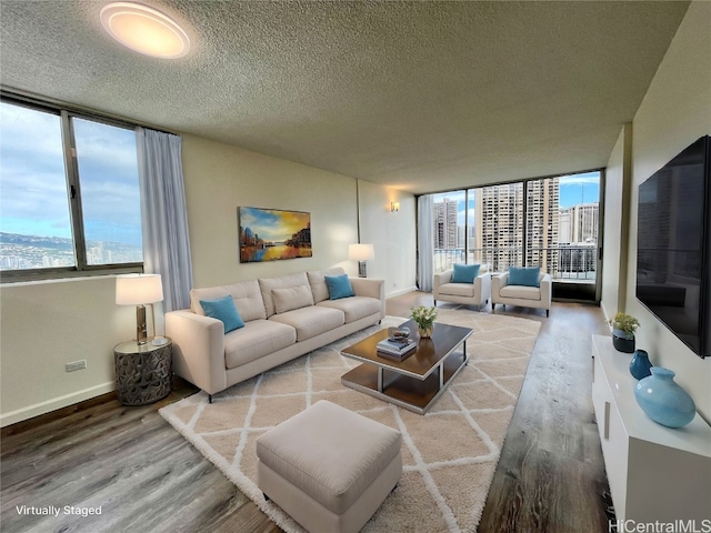 living room featuring plenty of natural light, a wall of windows, wood-type flooring, and a textured ceiling