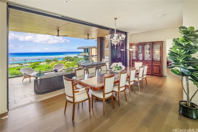 dining area featuring an inviting chandelier, hardwood / wood-style floors, and a water view