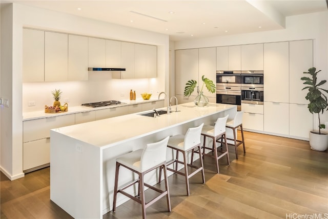 kitchen with a center island with sink, white cabinetry, and light hardwood / wood-style flooring