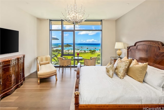 bedroom featuring a chandelier, a water view, light hardwood / wood-style floors, and expansive windows