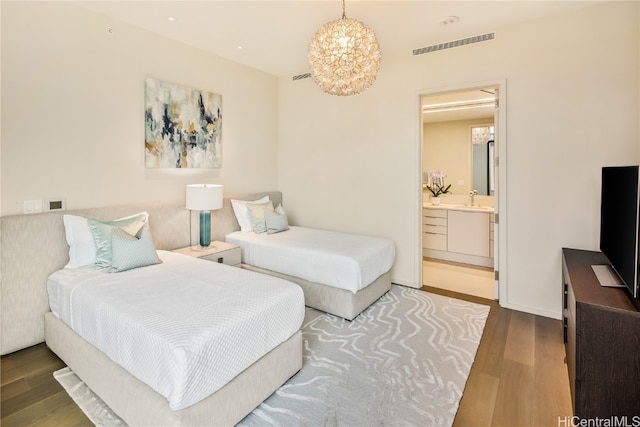 bedroom with sink, hardwood / wood-style floors, ensuite bathroom, and a chandelier