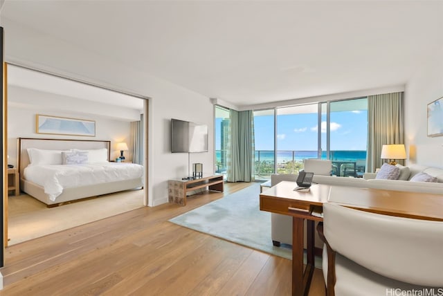 bedroom with expansive windows, light wood-type flooring, and access to outside