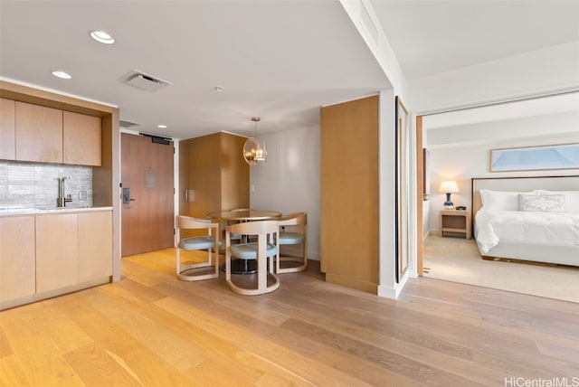 unfurnished dining area with sink, a chandelier, and light wood-type flooring