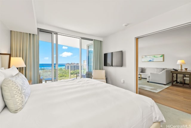 bedroom with expansive windows, hardwood / wood-style floors, and access to exterior