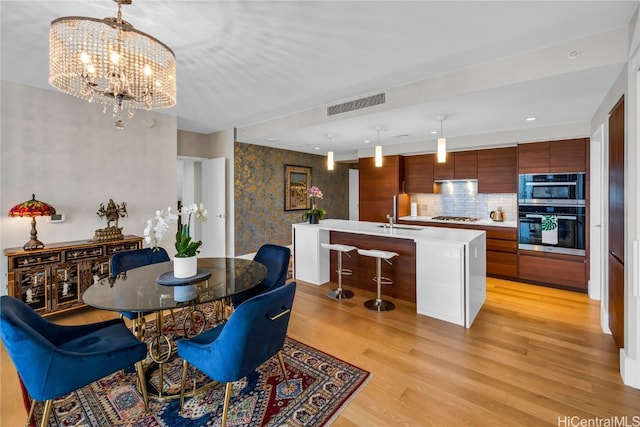 dining area with a chandelier, sink, and light wood-type flooring