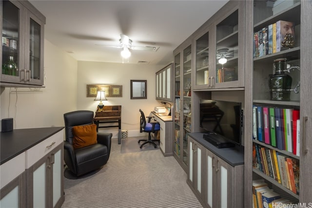 carpeted home office with built in desk and ceiling fan