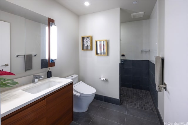 bathroom with vanity, a tile shower, tile patterned floors, and toilet