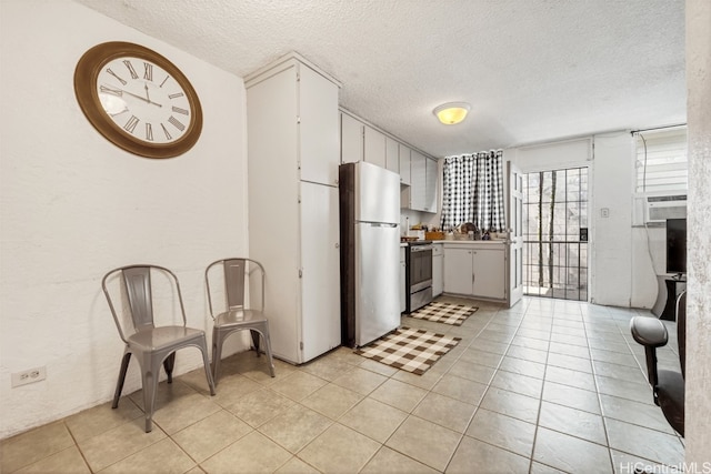 kitchen with stainless steel appliances, a textured ceiling, light tile patterned floors, and white cabinets