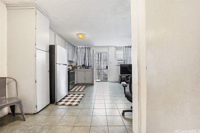 kitchen featuring light tile patterned flooring, appliances with stainless steel finishes, a textured ceiling, and white cabinets