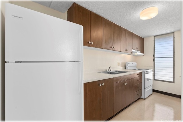 kitchen with white appliances, a textured ceiling, and sink